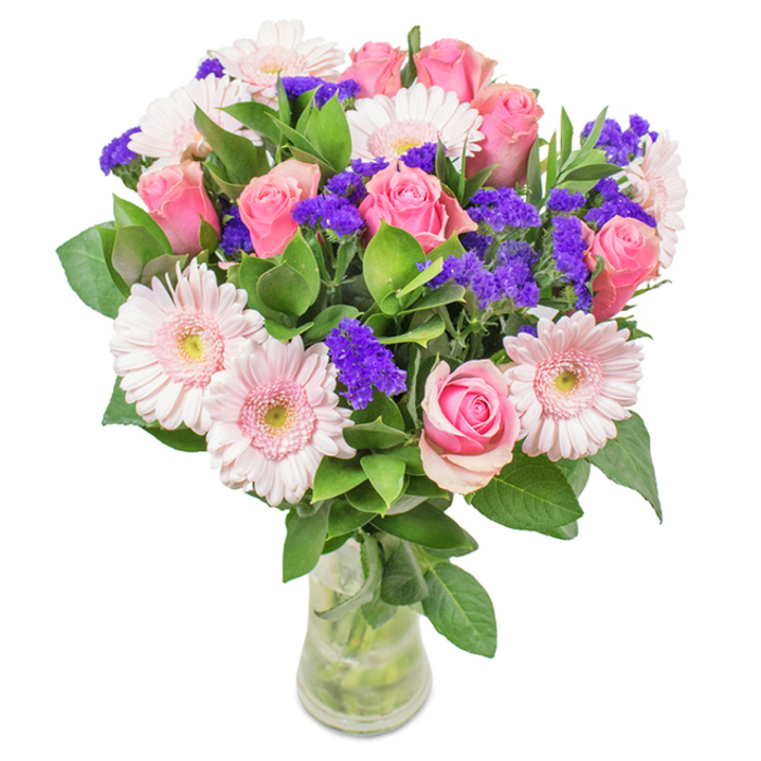 This lively, elegantly arranged bouquet from Bromley is presented in a clear glass vase, the stems meticulously trimmed and water visible for a sense of vibrant freshness. At its heart sit 7 to 9 medium pink roses, some buds tightly furled, others just starting to reveal their classic spirals-each petal a soft promise of affection. Encircling the roses are 5 to 7 pale pink gerbera daisies, immediately recognizable by their generous faces and numerous radiating petals that lend fullness and delicate whimsy to the design. Interspersed throughout are clusters of bright purple statice, adding rich texture and a deeper note of colour, reminiscent of the wildflowers found near Church House Gardens. The arrangement is anchored by lush, deep green foliage, lending a sense of natural abundance. Housed in the transparent vase, the bouquet carries a contemporary yet timeless appeal, well-suited for birthdays, Mother's Day, or as an elegant welcome gift for a new Bromley neighbour. Each flower is chosen with intention, bringing joy and celebration to the heart of local homes and offices.